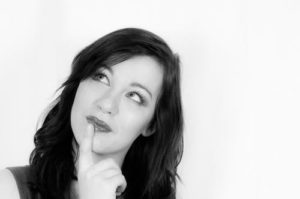 woman thinking about something with her head tilted to one side and looking off into space against white background