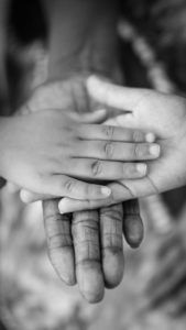 hands stacked on top of each other on a black and white background