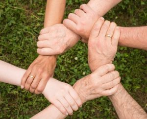 family hands in a circle above grass