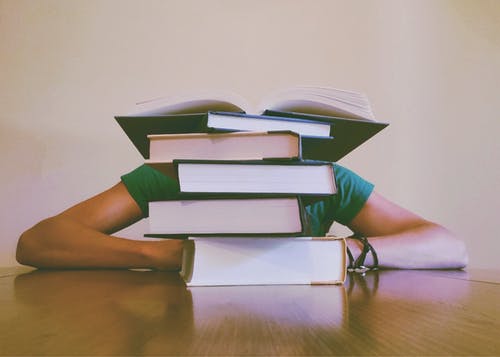 person behind a stack of books sitting at a table, search