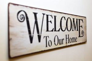 wooden welcome to our home sign on a white wall