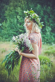 Nordic woman wearing flower wreath carrying foliage