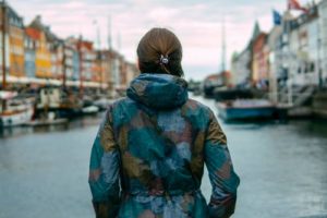 woman facing a canal with buildings on each side in a Danish town