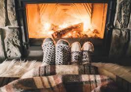 Danish hygge with stockinged feet in front of fireplace under a warm blanket